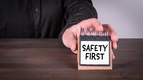 A businessman places a small sign on a table, reading Safety First.