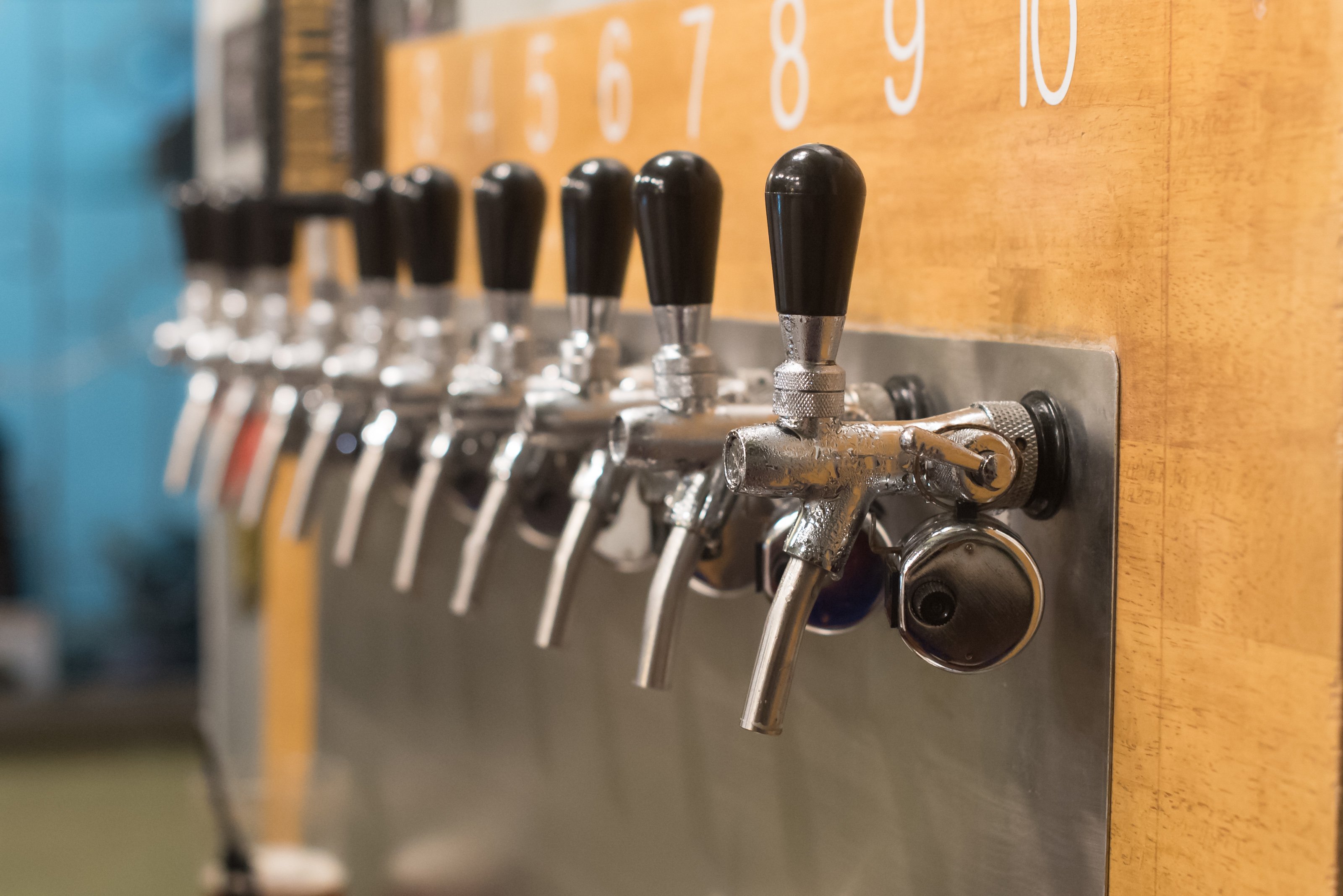 Close-up of ten draft beer taps at a brewery.