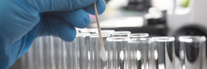 A person swabbing a cue tip inside a test tube.