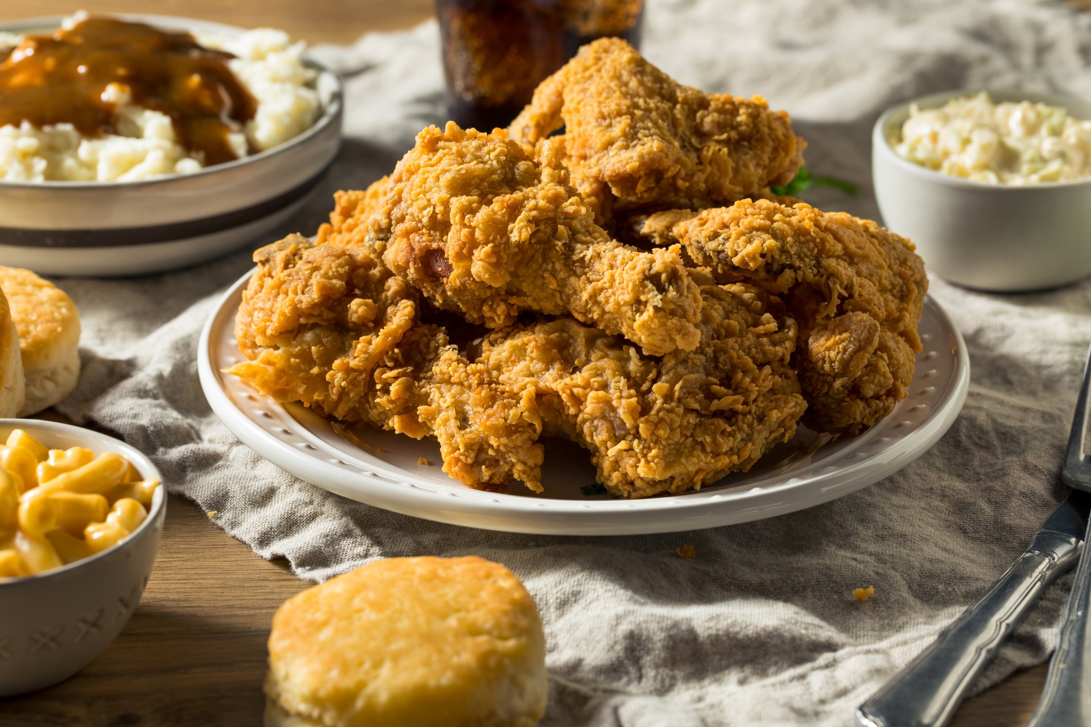 A plate of fried chicken surrounded by biscuits, mashed potatoes, and mac and cheese.