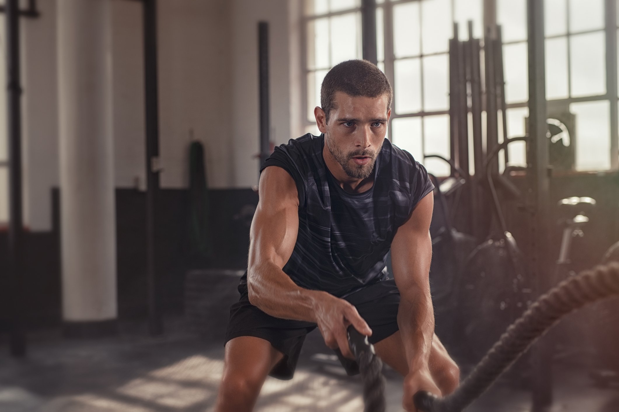 Man working out with ropes in a gym.