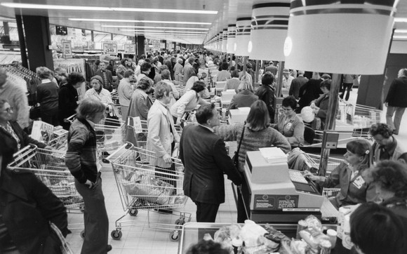 A black and white image of crowded grocery store checkout lines