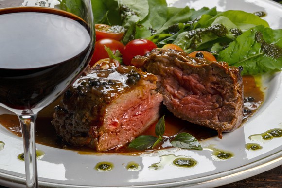Steak on a plate with a glass of wine