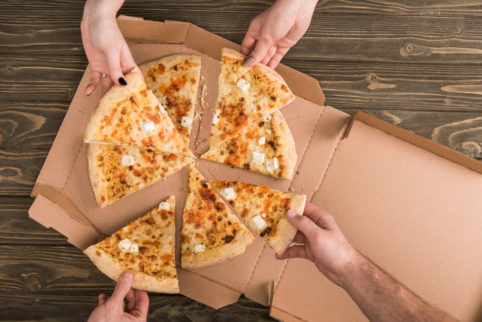 Four people sharing a pizza out of a box.