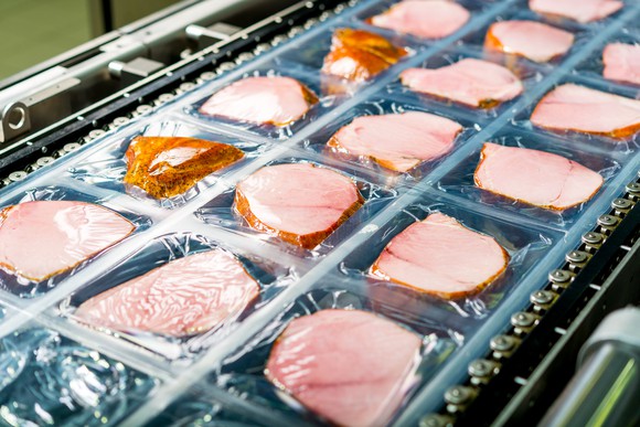 Ham being processed and packaged on an assembly line.