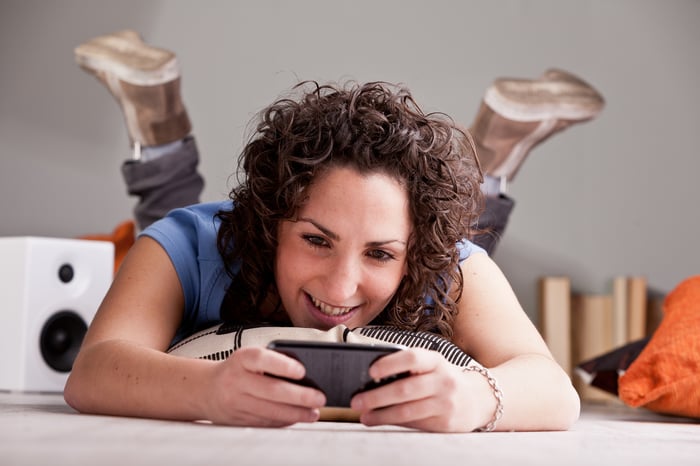 A young woman laying on the floor using a smartphone.