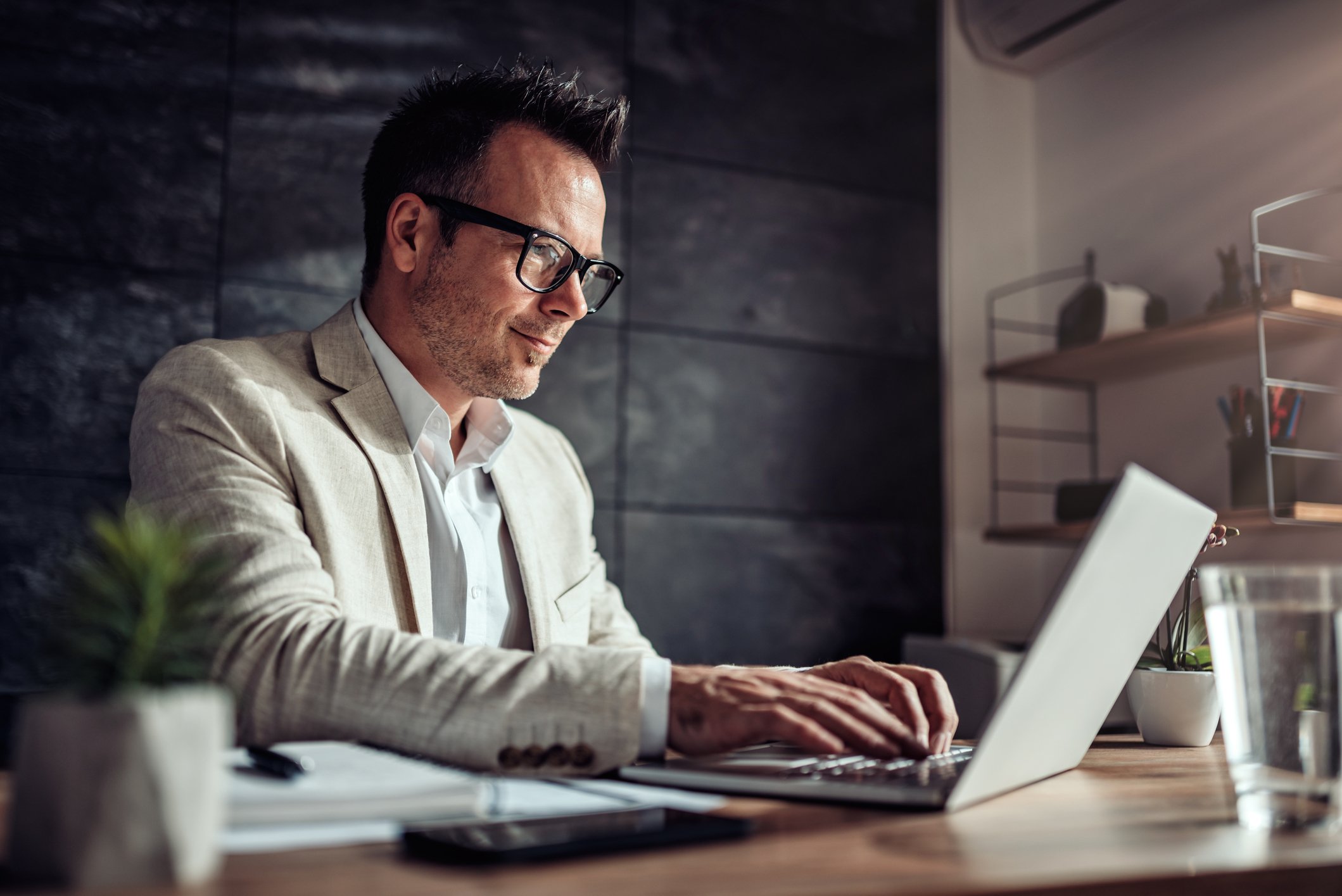 A man uses a laptop at a desk.