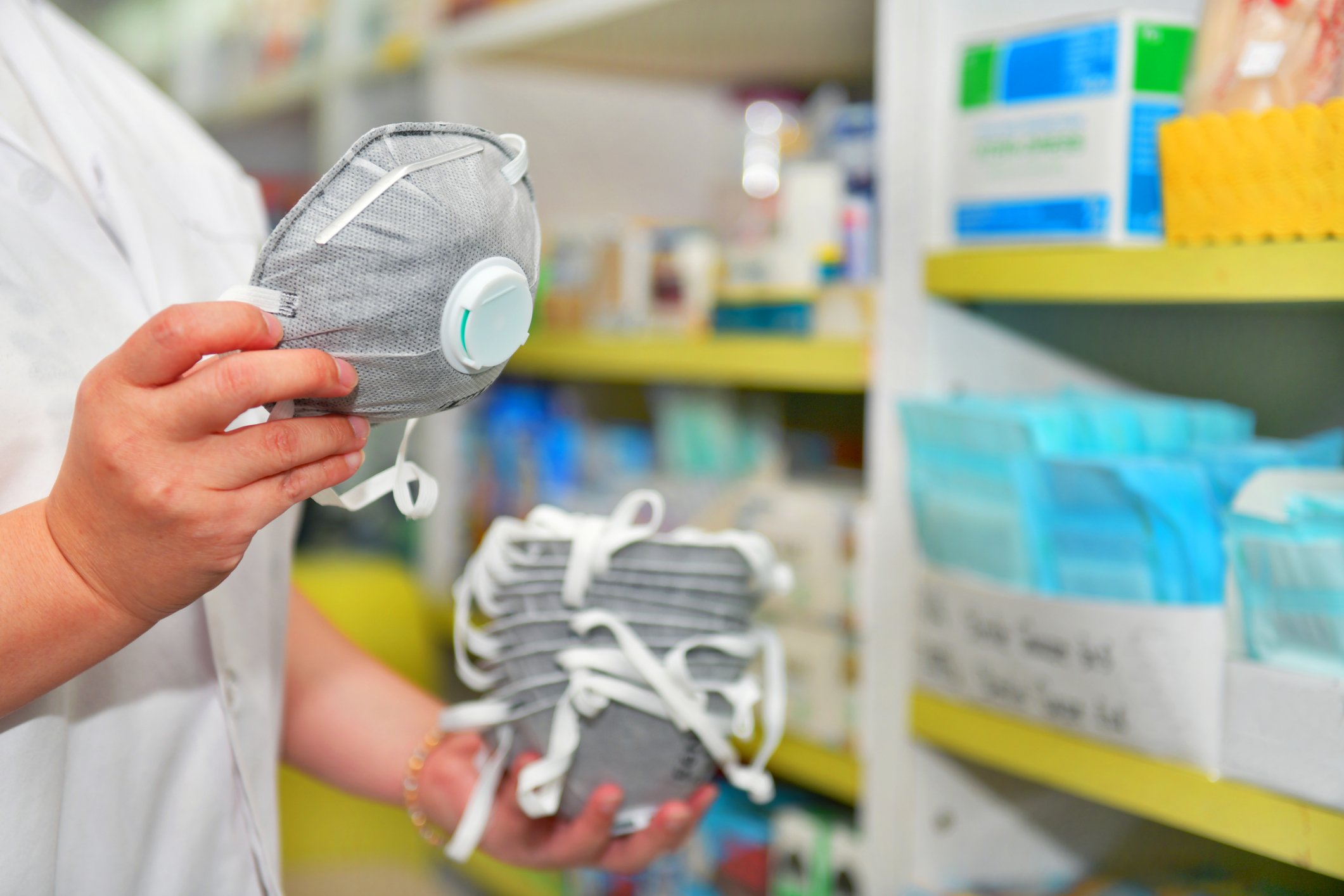 healthcare worker holding stack of respirator masks in supply room