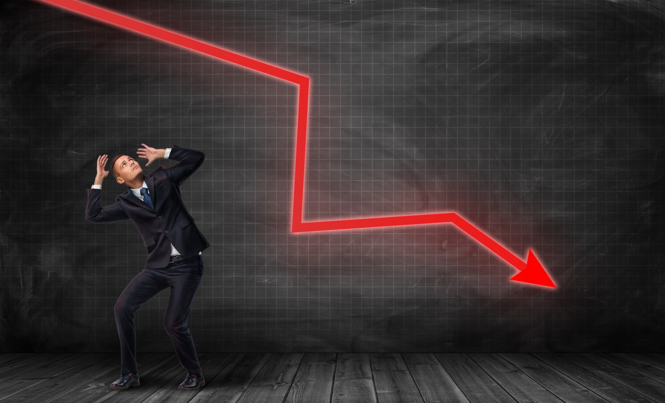 A scared investor recoils under a down-trending red arrow.