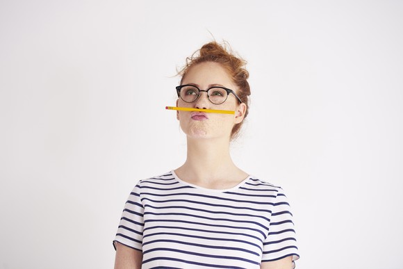 Bored woman holding pencil under her nose