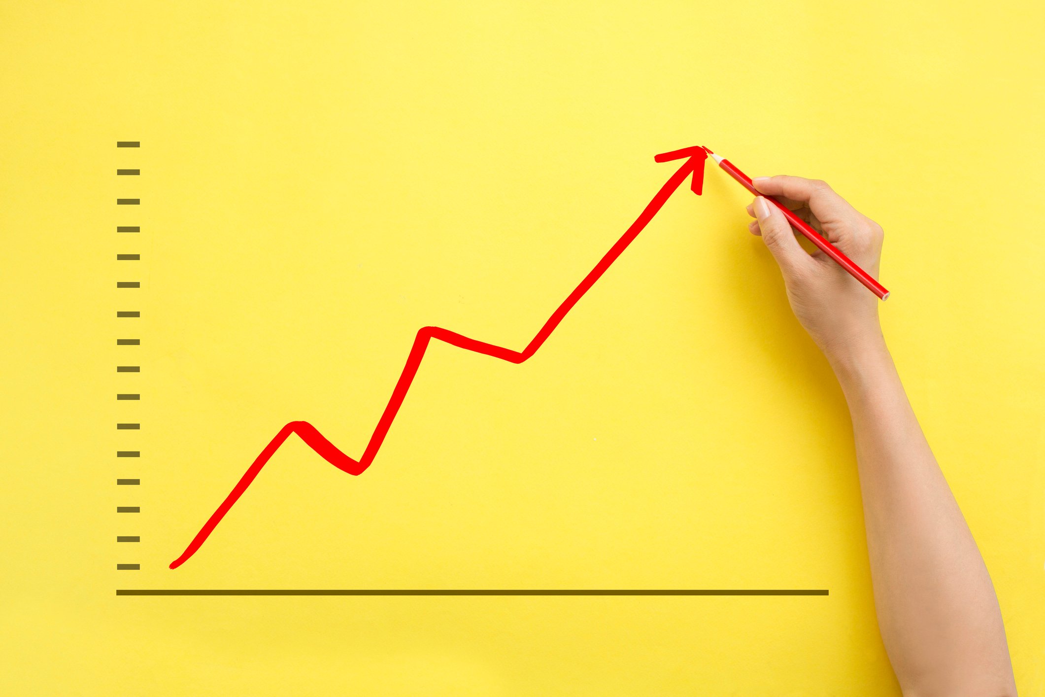 A person draws an upward trendline on a large piece of paper.