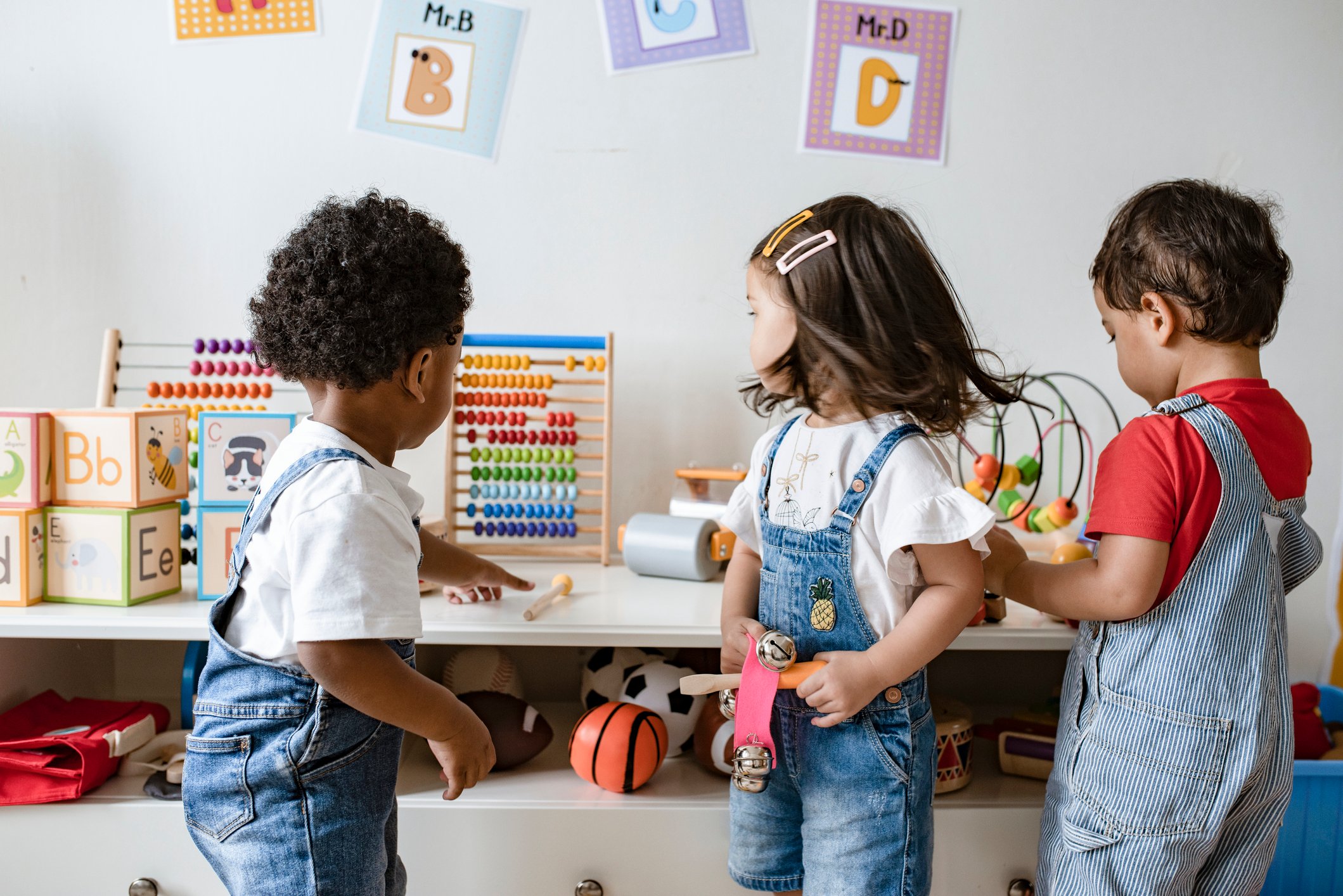 Three children playing with toys in a playroom.
