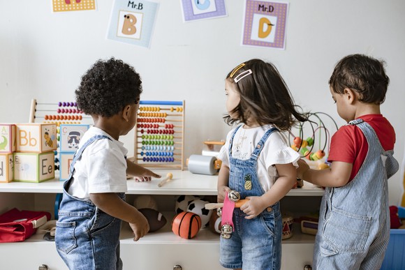 Three children playing with toys in a playroom.