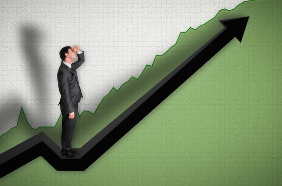 Person in a suit looking up at an upward sloping chart.