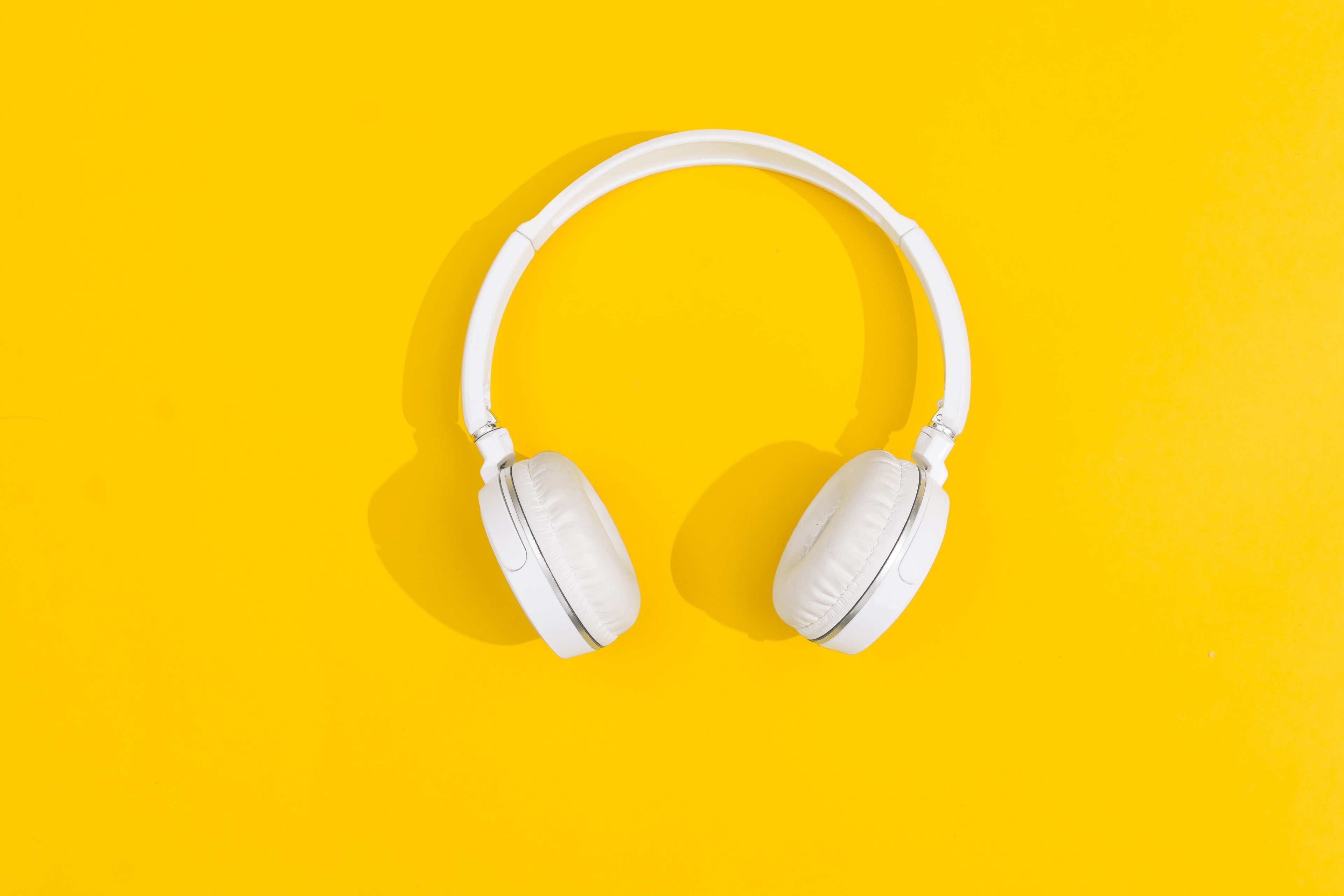 White over-the-ear headphones with a yellow background. 