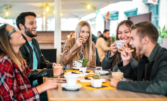 Five friends hanging out at a coffee shop enjoying each other's company.