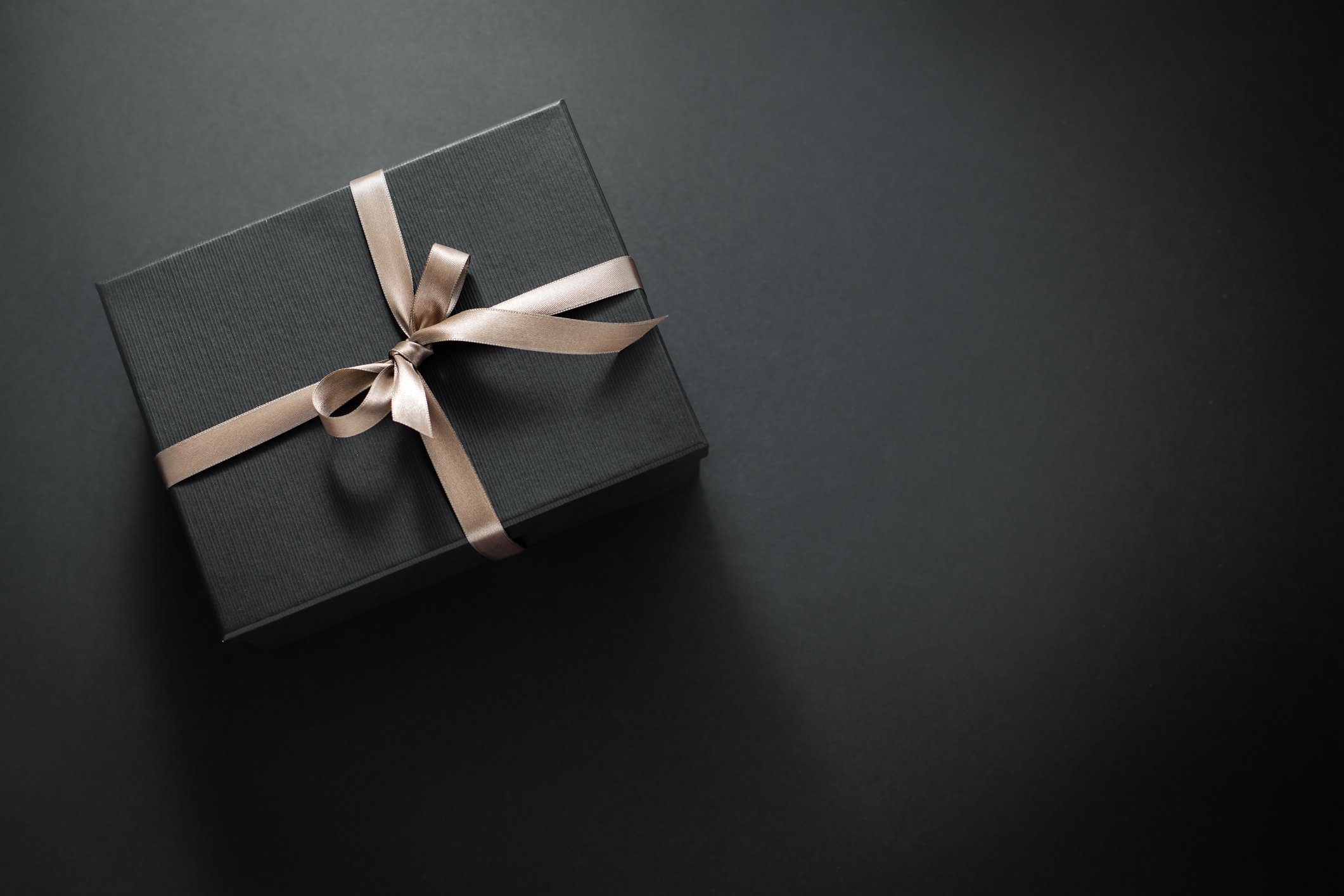 A gift wrapped in dark paper on a dark background.