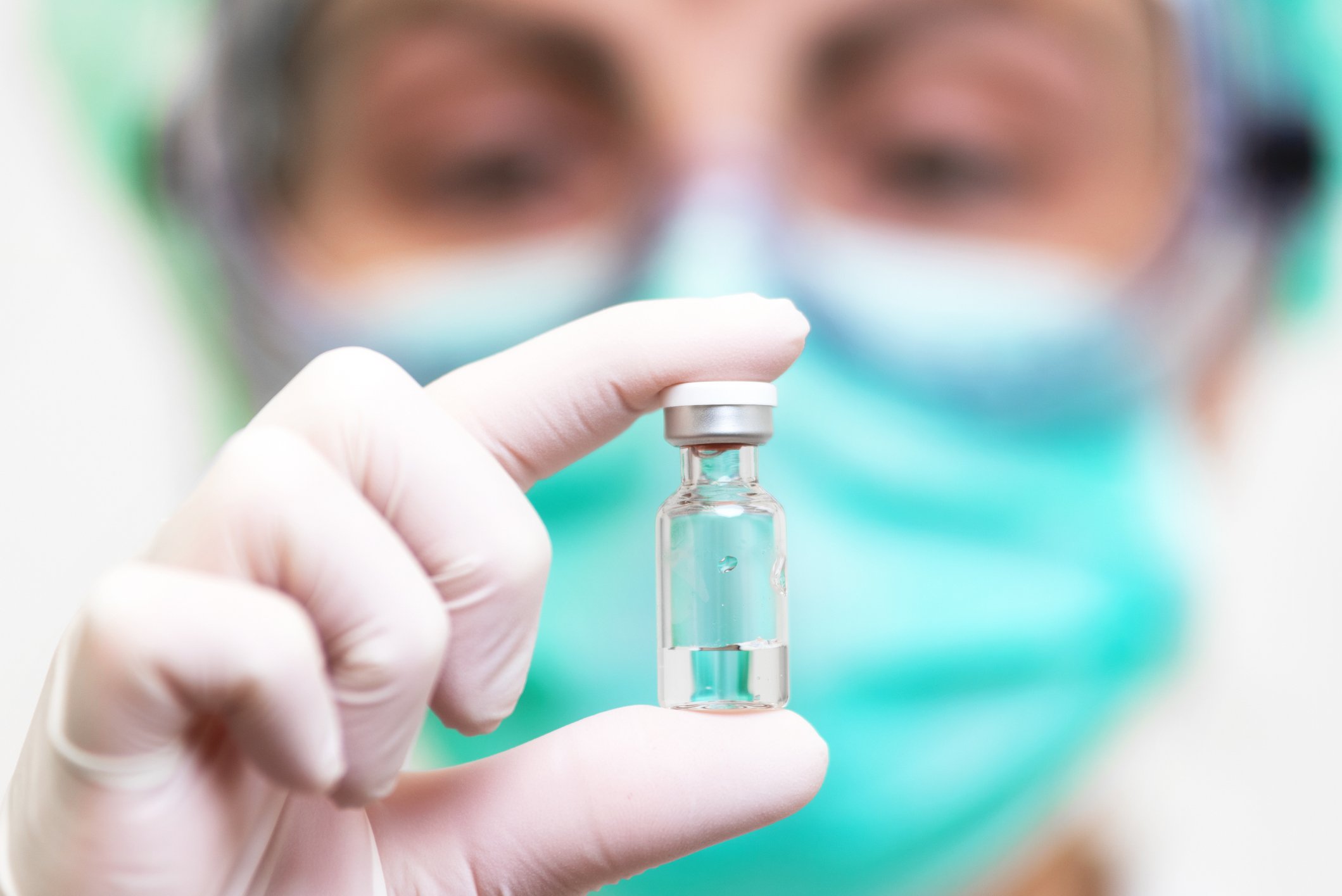 Medical professional with a face mask holding a vaccine bottle