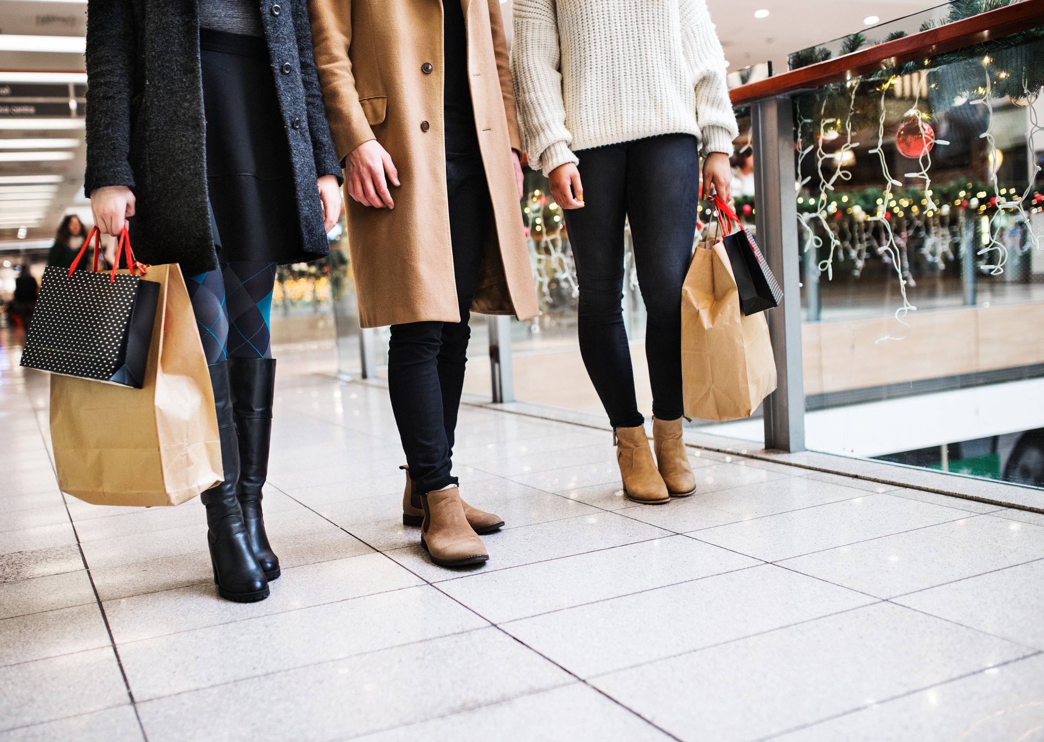 Three women carrying shopping bags in a mall