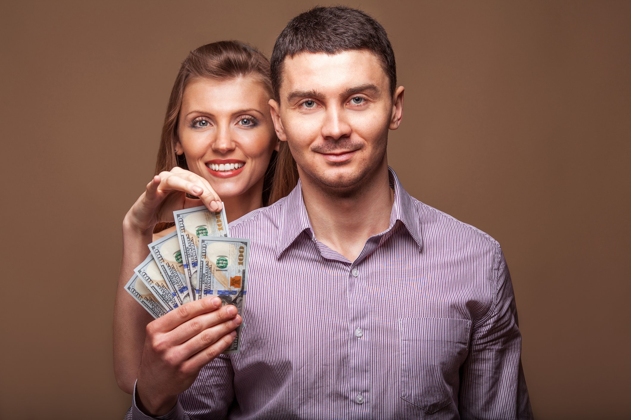 A young man and woman holding a handful of cash.