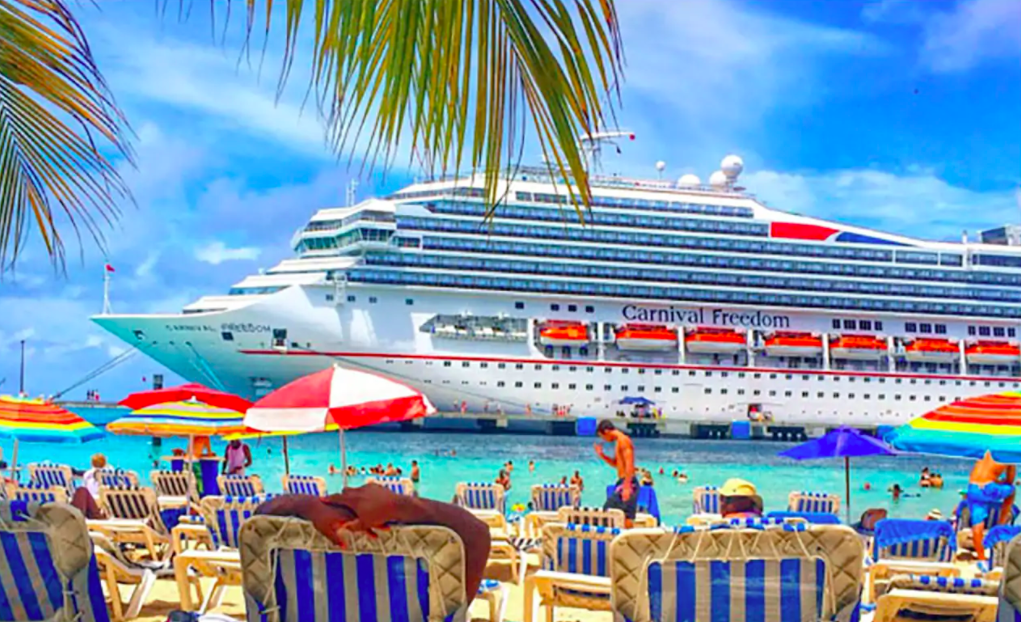 Carnival Freedom docked near a private beach.
