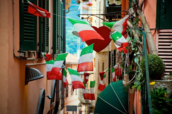 Italian flags hanging in a crowded street.