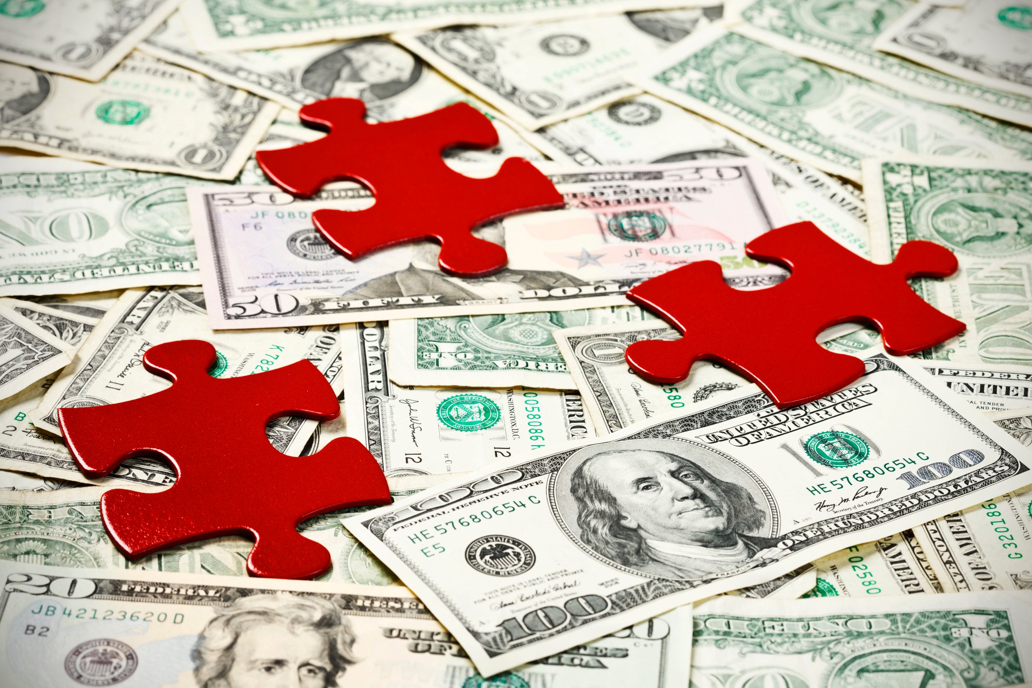 3 red jigsaw puzzle pieces with money
