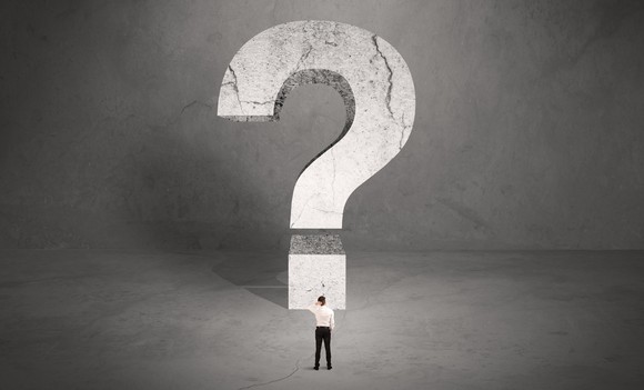 Man standing with hand on his head in front of a giant question mark