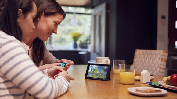 A mother and daughter playing a game on the Nintendo Switch on the kitchen table.