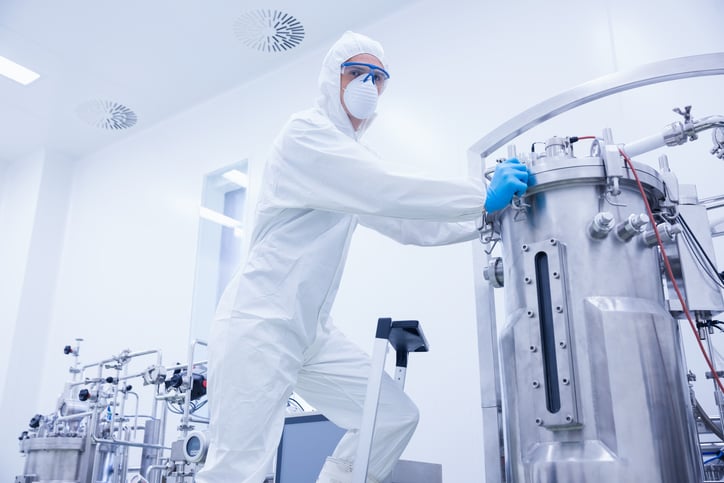 A technician moving a reactor in a drug manufacturing facility.