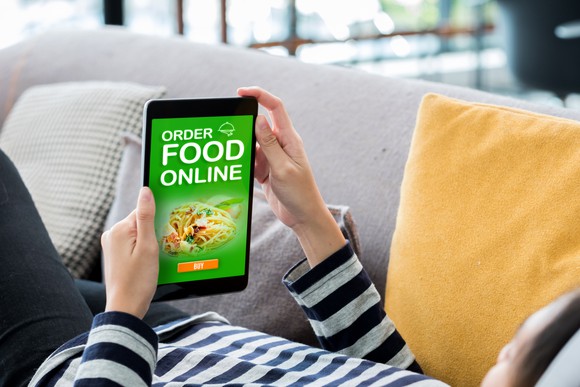 A customer ordering food delivery while lying on their sofa at home.