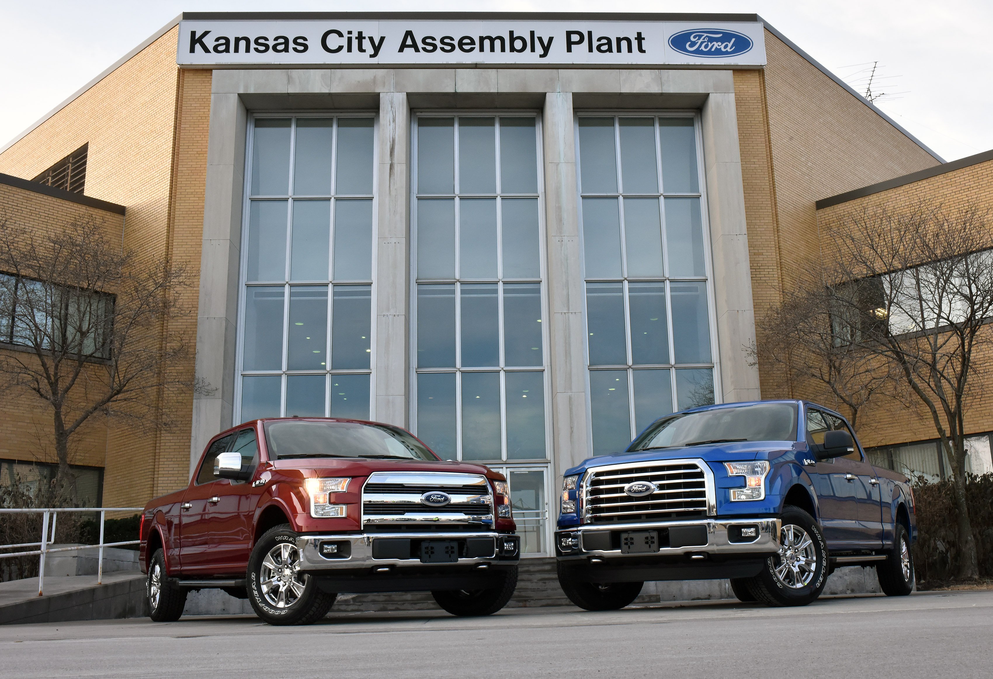 The front of Ford's Kansas City Assembly Plant, with two Ford pickup truck parked outside.