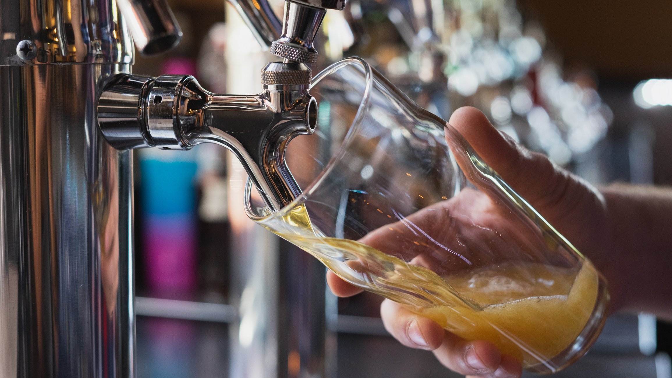 A bartender pours beer into a glass from the tap.