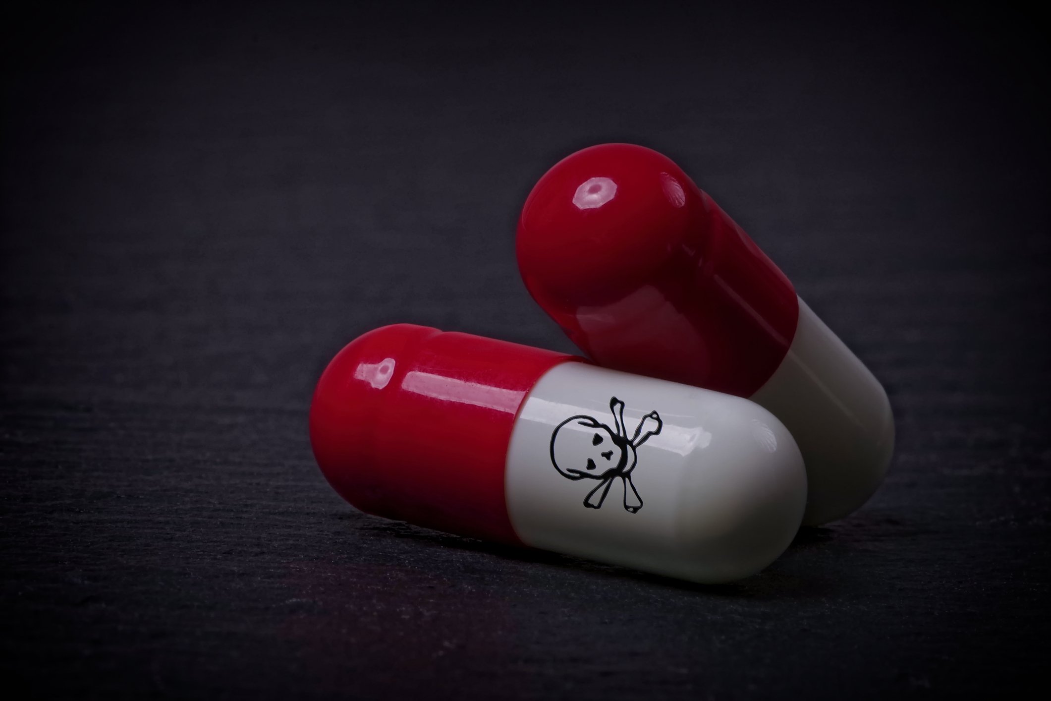 Two pills bearing the skull-and-crossbones poison symbol.