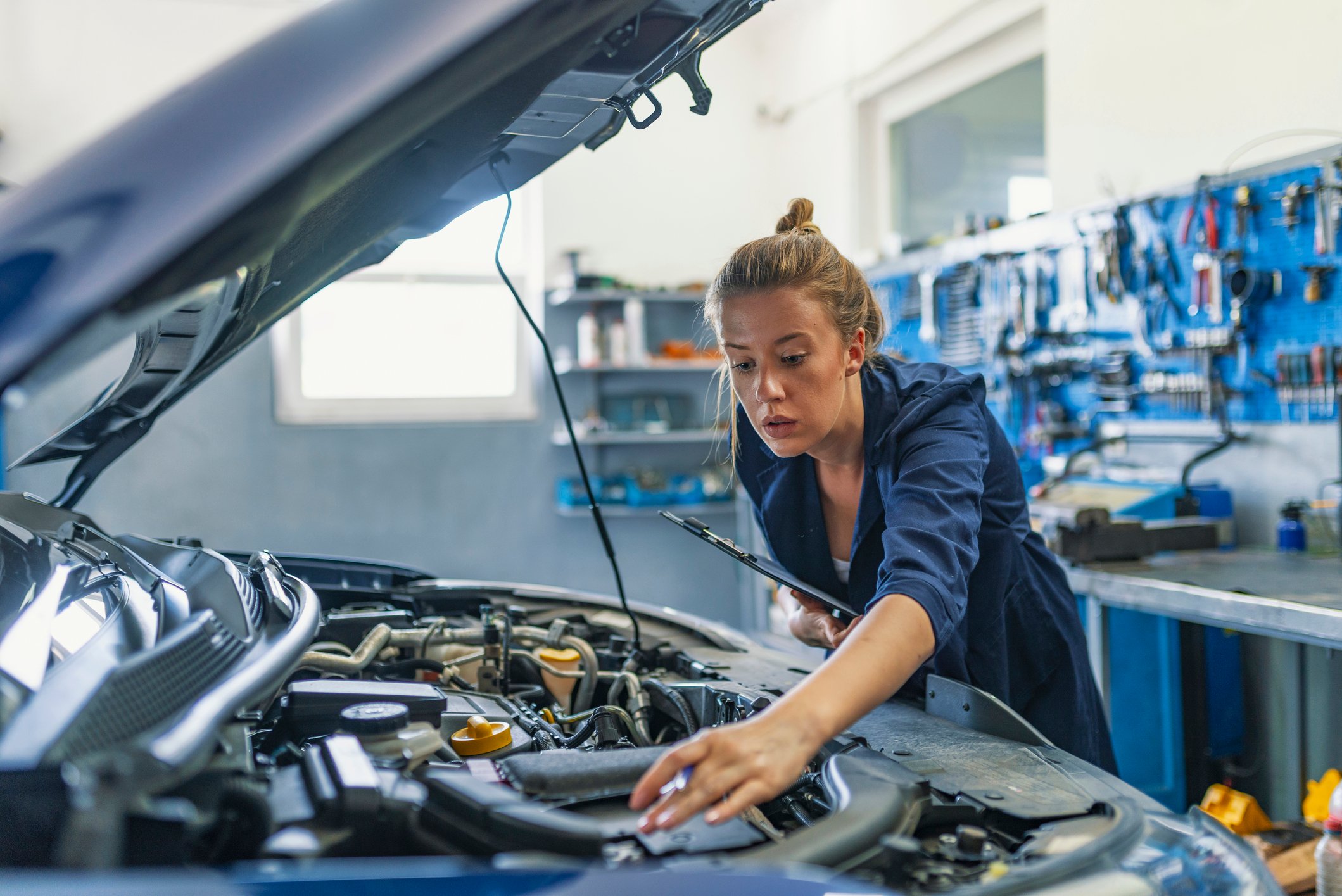 An auto mechanic assessing a car's engine. 