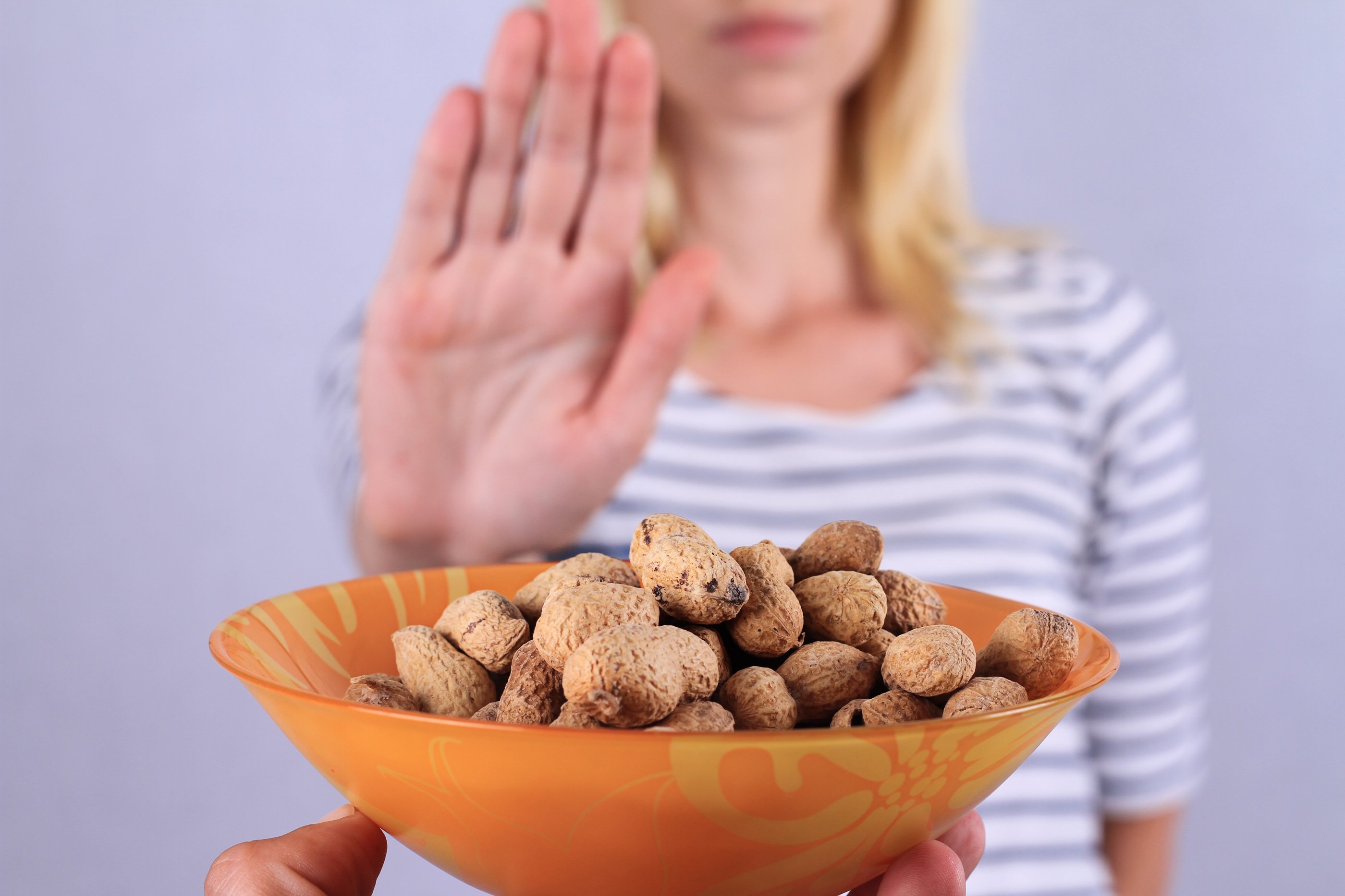 Girl with hand up saying no to bowl of peanuts