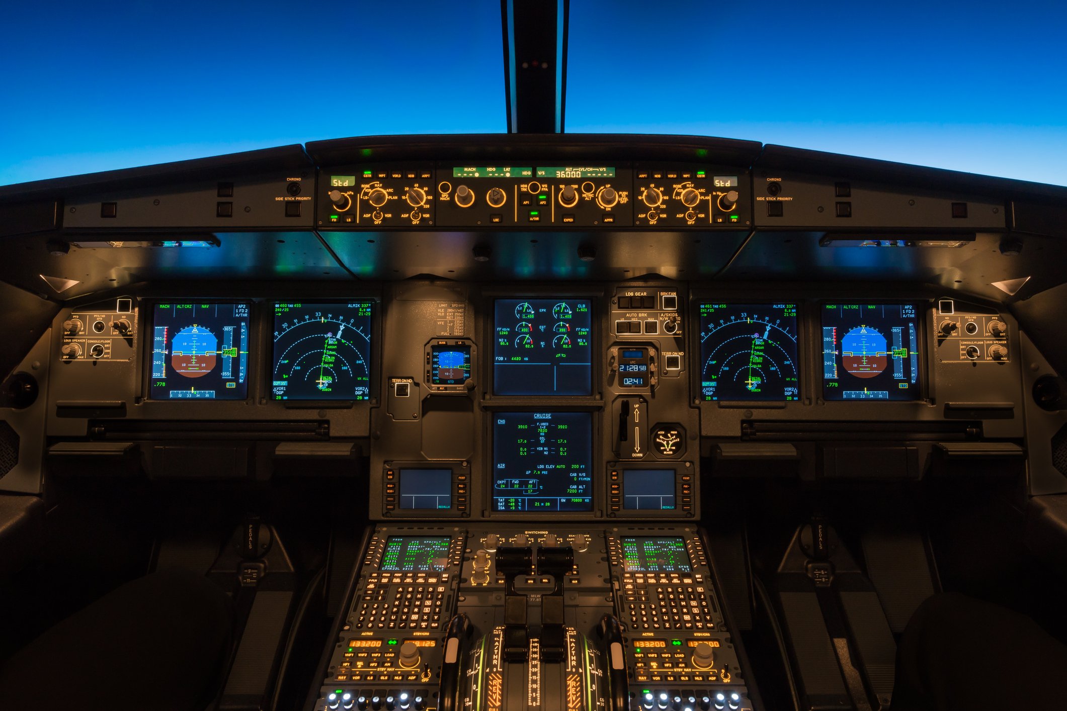 A passenger jet cockpit at night with the electronic avionics and instruments lit up