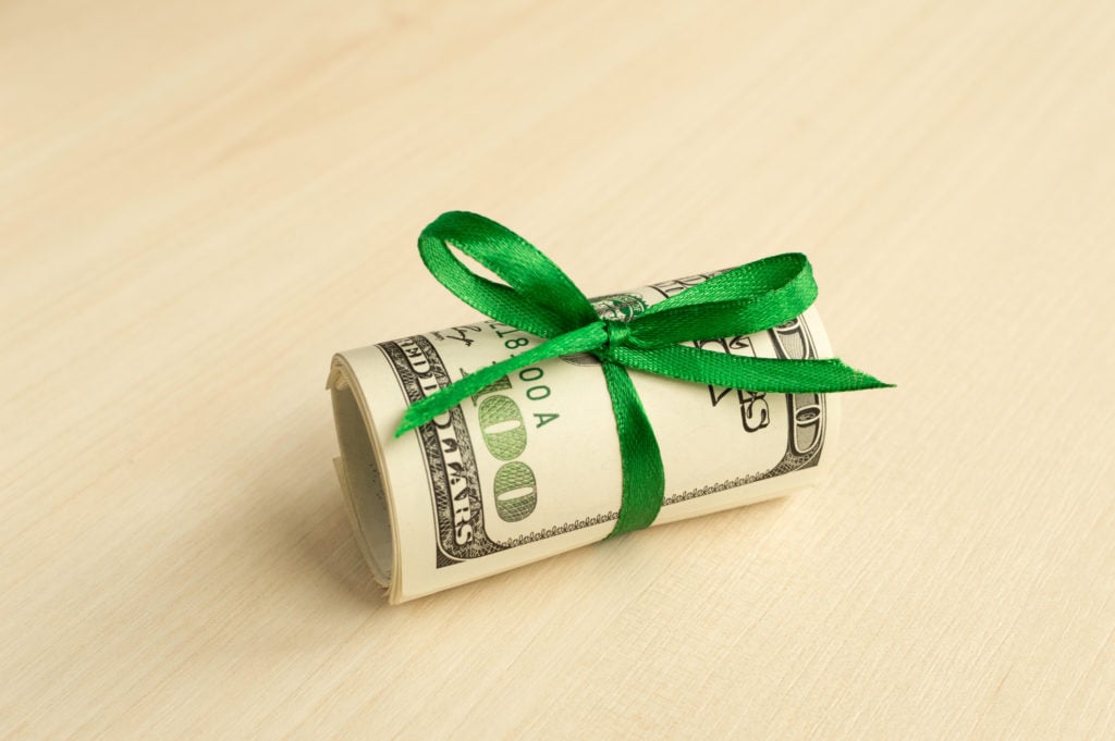 A roll of hundred-dollar bills tied together by a green ribbon.