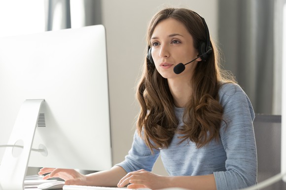 Young woman wearing a headset and staring at her PC monitor.
