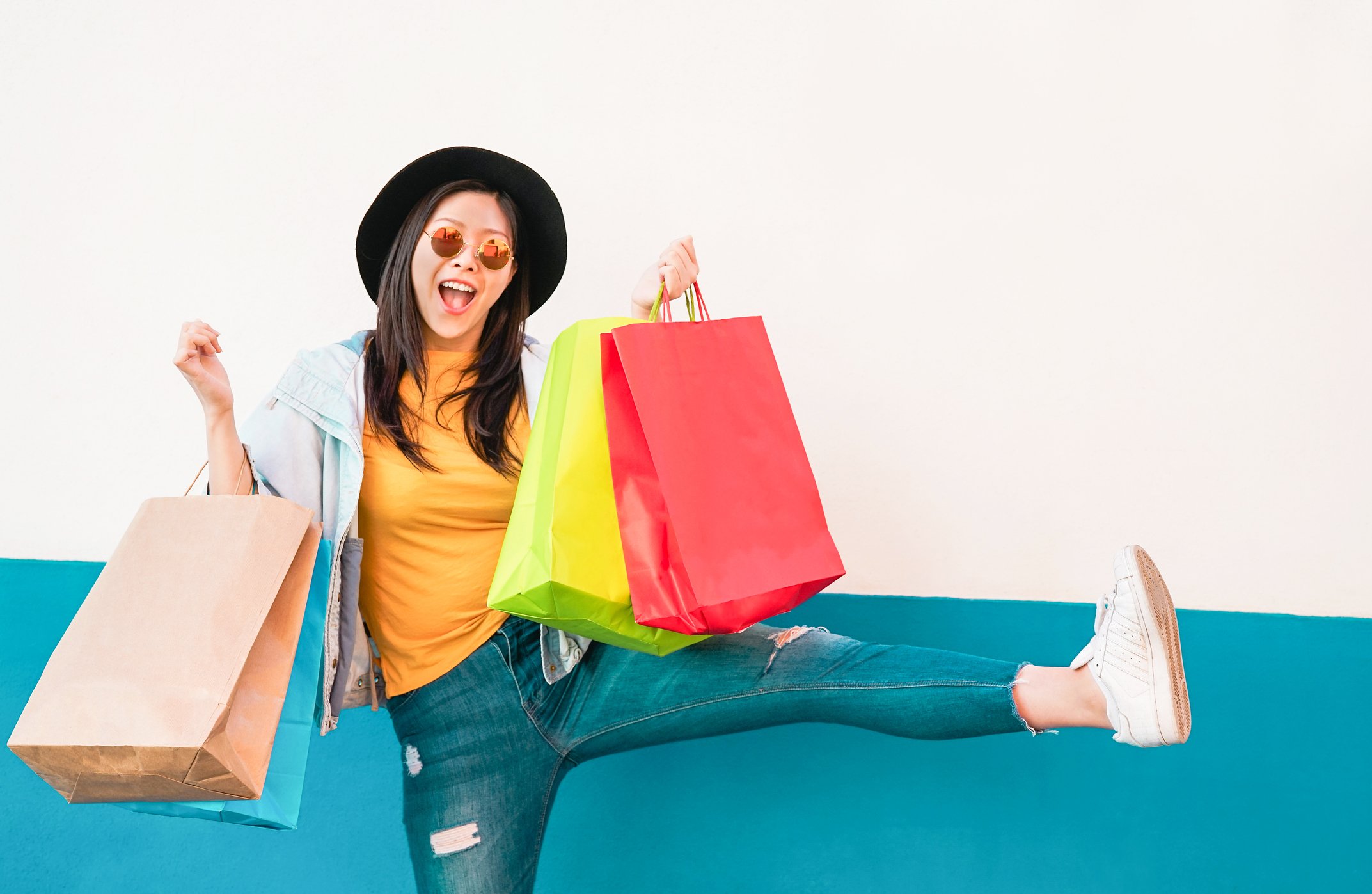 A happy woman carries several shopping bags.