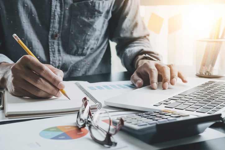 A man performing calculations at his desk with a pencil and calculator.