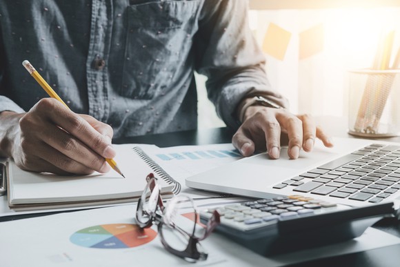 A man performing calculations at his desk with a pencil and calculator.