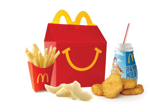 A kids Happy Meal, with fries, apple slices, chicken nuggets, and a cup of milk.