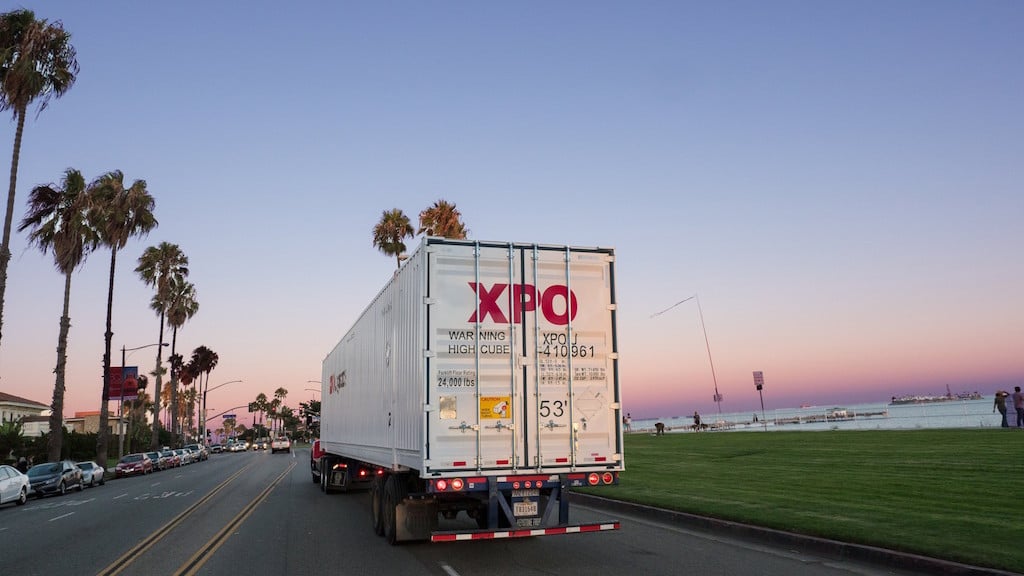 An XPO truck on a coastal road.