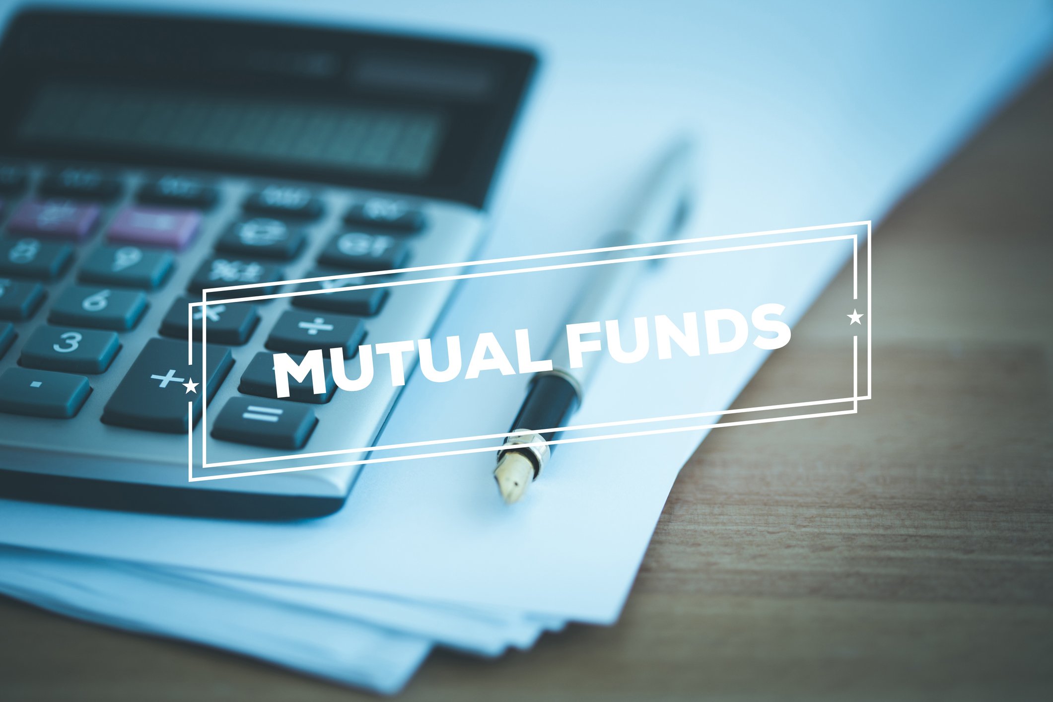 A calculator sitting on a stack of paper with the word "mutual funds" stamped across the top.