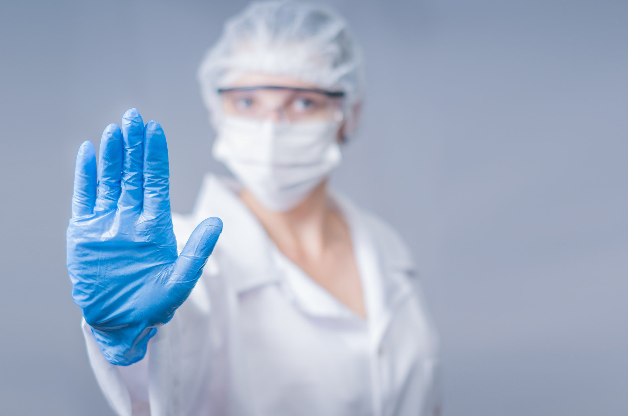 Healthcare professional with their hand up.