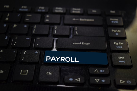 A computer keyboard with the word payroll written on the long shift key.