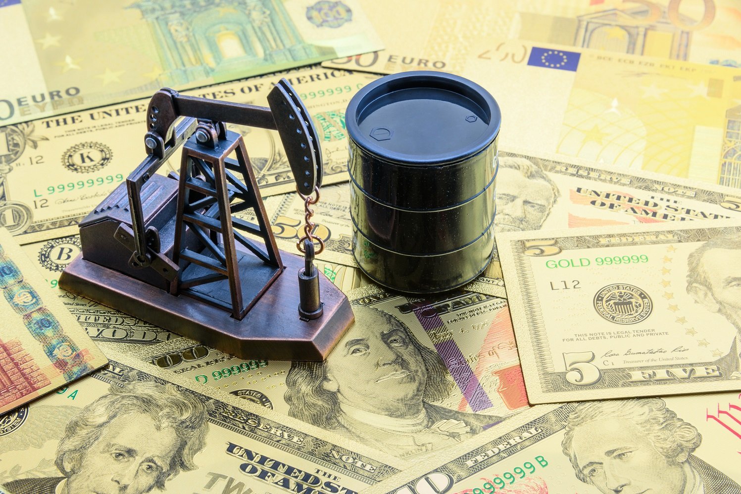 Oil barrel and pumpjack paperweight on top of paper money.