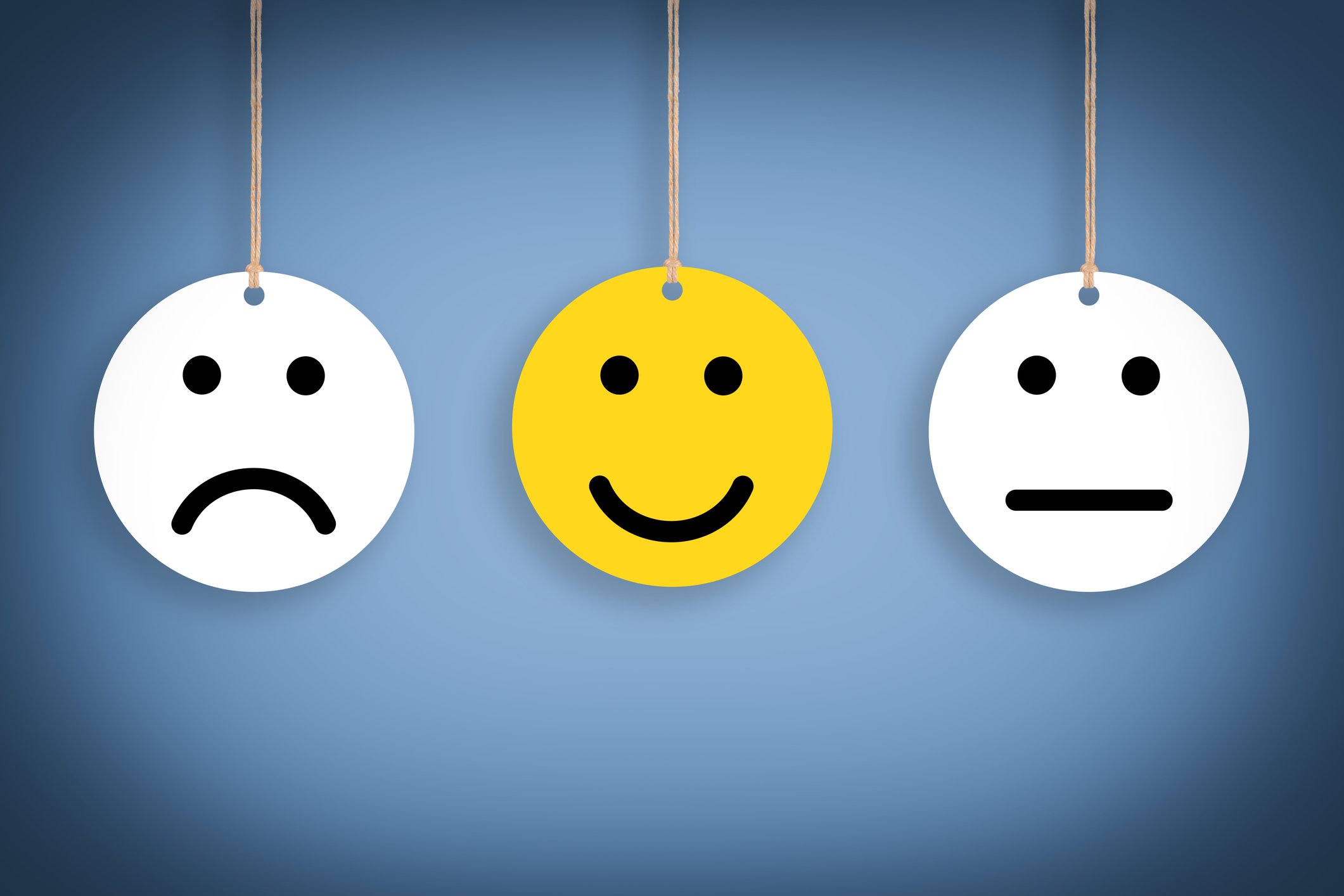 Yellow smiley face in between a white frowning face and a white stoic face