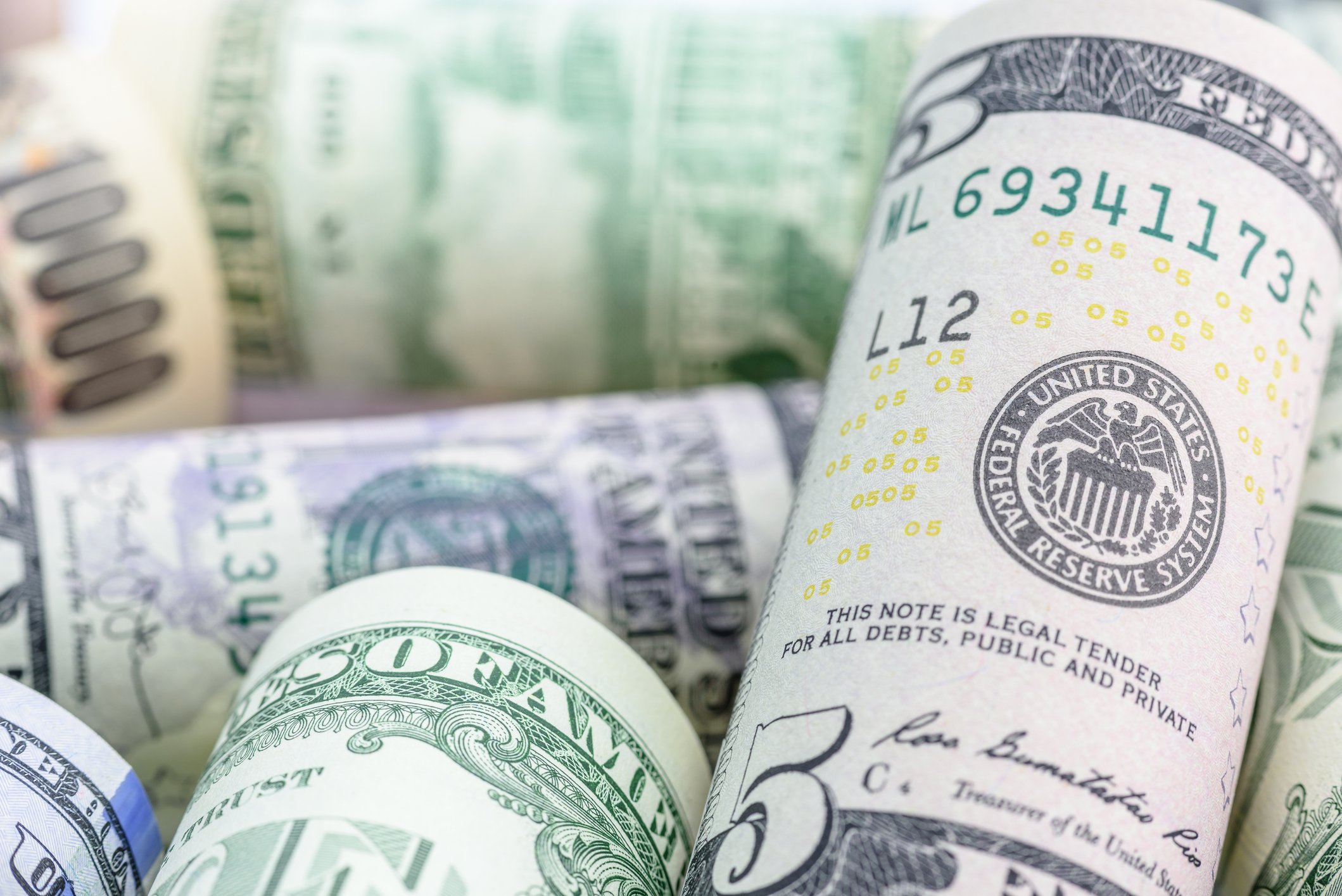 Various denominations of US dollar bills rolled up on a table